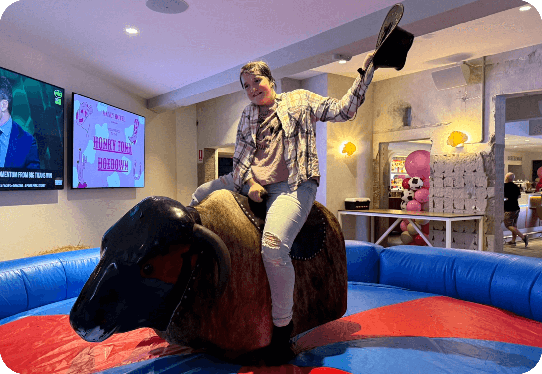 Person riding mechanical bull in indoor setting.